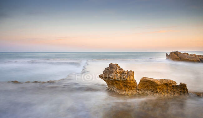 Picturesque view of rocks on coast between fog near water surface and wonderful heaven — Stock Photo