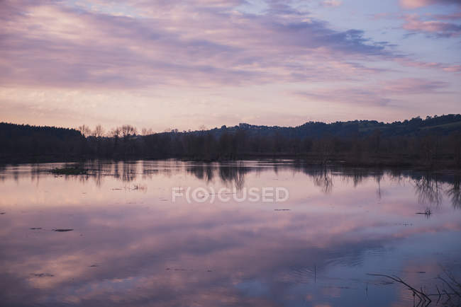 Хмарне вечірнє небо над спокійним озером у сільській місцевості — стокове фото