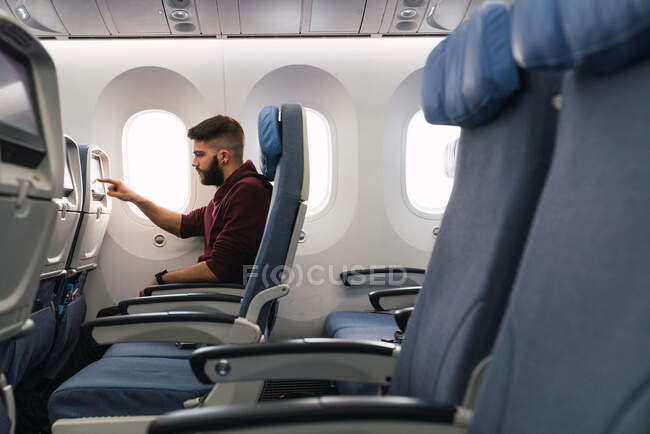 Бородатий пасажир використовує пристрій у літаку — стокове фото