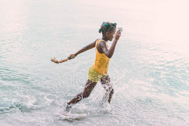 Side view of African American teenager with toys going in sea in Jamaica — Stock Photo