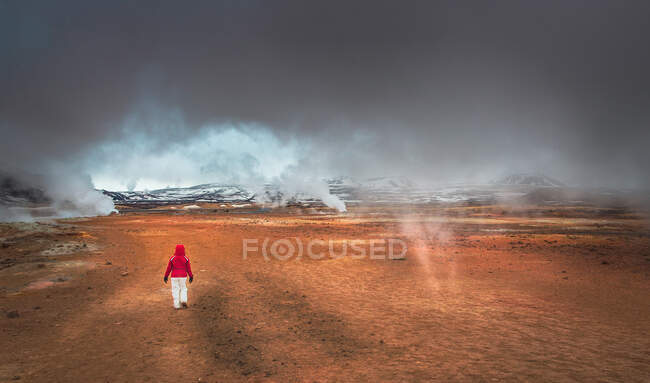 Visão traseira da pessoa anônima andando em vales incríveis perto de gêiseres majestosos na Islândia — Fotografia de Stock