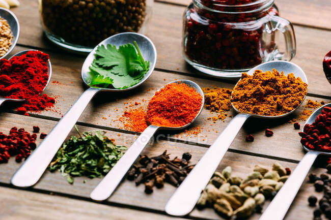 Bunch of assorted spices placed in order on lumber tabletop near bottle of oil — Stock Photo