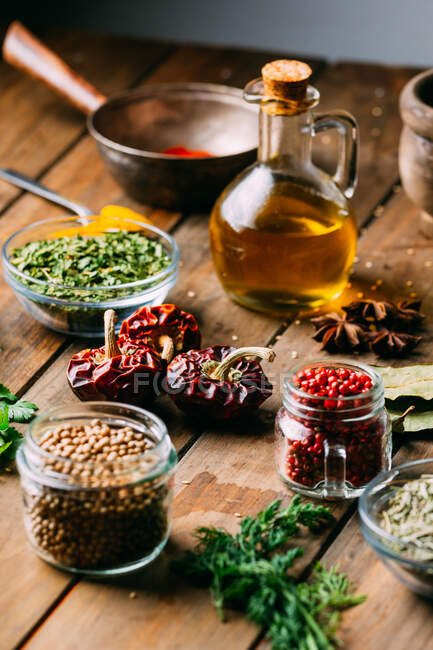 Spezie ed erbe aromatiche assortite e bottiglia di olio posta su un tavolo  di legno — cucina, legname - Stock Photo