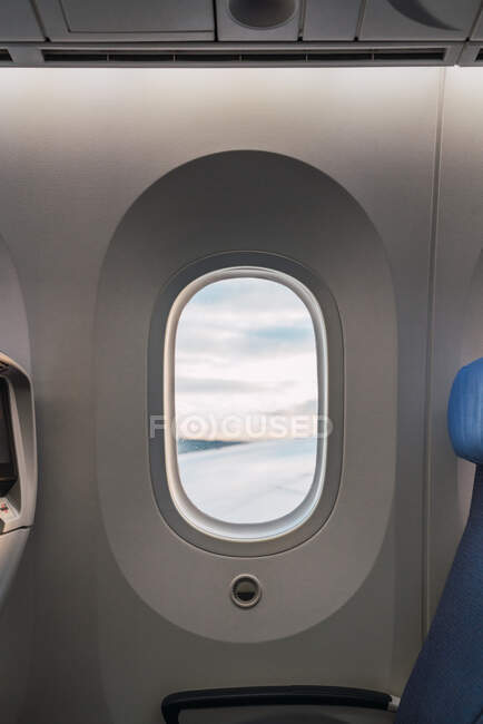 Fenster des modernen Flugzeugs mit Blick auf den bewölkten Himmel — Stockfoto