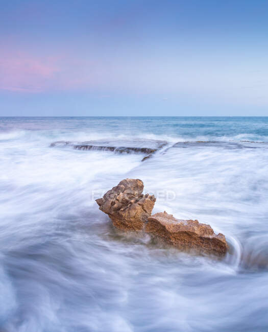 Удивительные камни на берегу у воды и голубого неба — стоковое фото