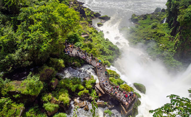 Vista aérea del grupo de turistas de pie en la terraza cerca de la cascada de Iguazú en Argentina - foto de stock