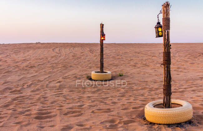 Deux enjeux avec de petites lanternes coincées dans le sable sur un désert incroyable aux Emirats Arabes Unis — Photo de stock