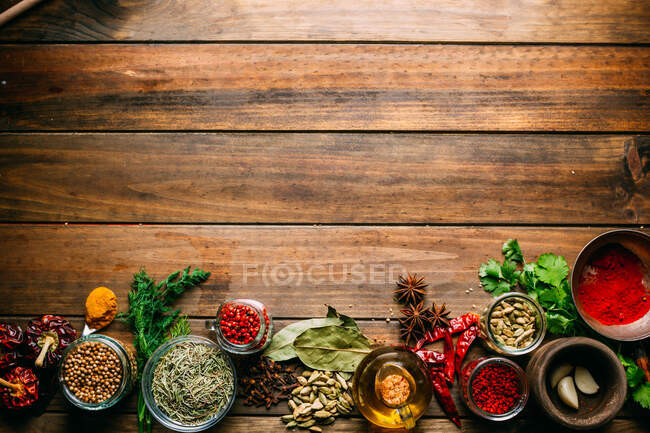 Assortiment d'épices et d'herbes et bouteille d'huile placée sur une table en bois — Photo de stock