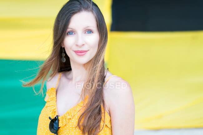 Charming beautiful young woman with sunglasses on yellow blouse looking at camera on blurred background in Jamaica — Stock Photo