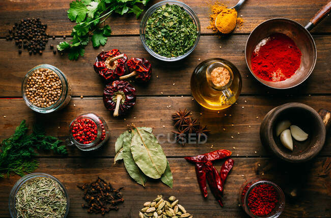 Spezie ed erbe aromatiche assortite e bottiglia di olio posta su un tavolo di legno — Foto stock