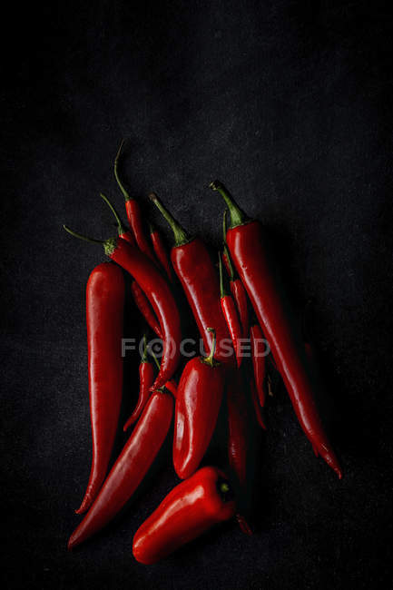 Fresh red spicy chilli peppers on black background — Stock Photo