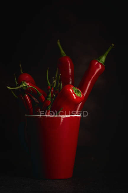 Pimentos de pimenta picante vermelha fresca na xícara no fundo preto — Fotografia de Stock