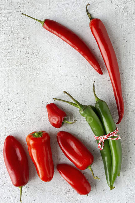 Pimentas picantes vermelhas e verdes frescas no fundo branco — Fotografia de Stock