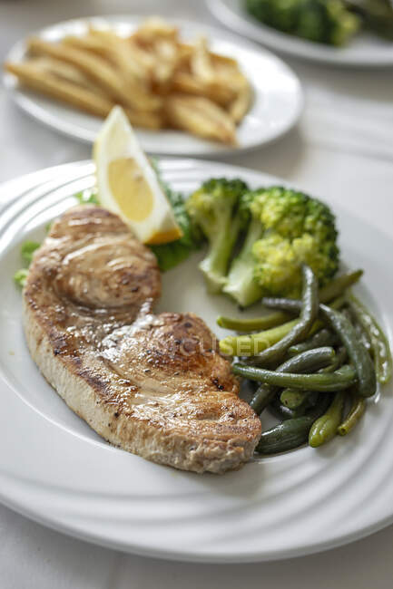 Tavolo ristorante pronto da mangiare. Posate, tovaglioli, tazze; piatti. pesce spada; verdure — Foto stock