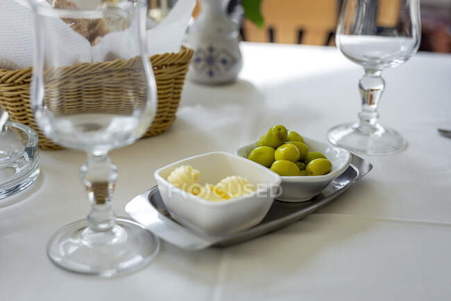 Table de restaurant prête à manger. Couverts, serviettes, tasses ; plats. Beurre ; olives, — Photo de stock