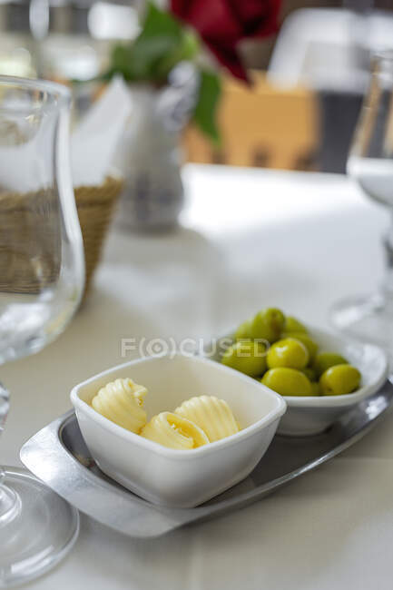 Restaurant table ready to eat. Cutlery, napkins, cups; dishes. Butter; olives, — Stock Photo