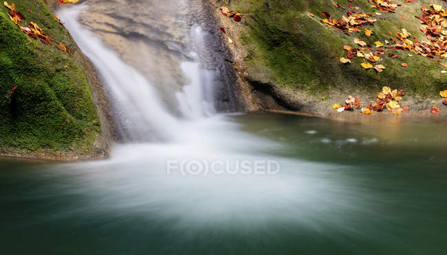 Turquoise water in reservoir with waterfall and green rocks, Navarra — Stock Photo