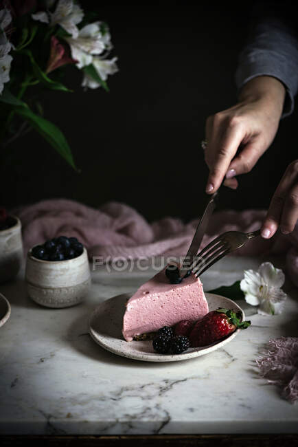 Обрезанное изображение женщины, разрезающей ягодный торт — стоковое фото