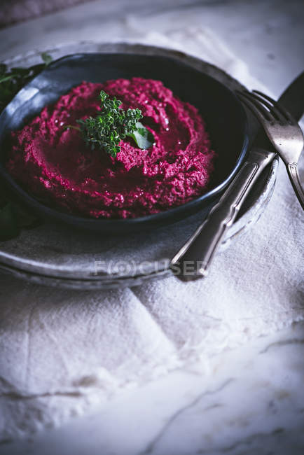 Домашний свекольный хумус на тарелке с травами — стоковое фото