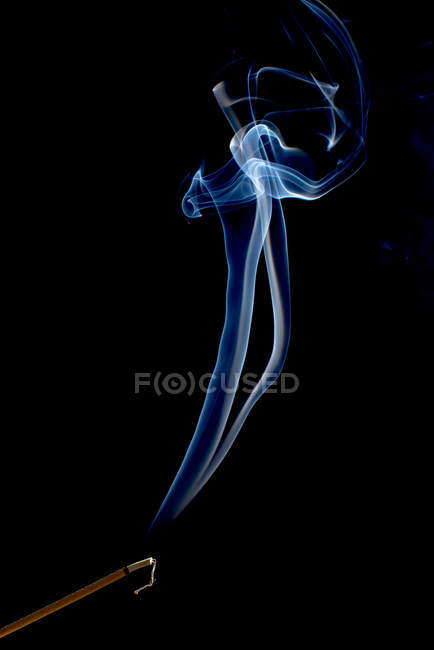 Remolinos de humo azul brillante sobre fondo negro - foto de stock