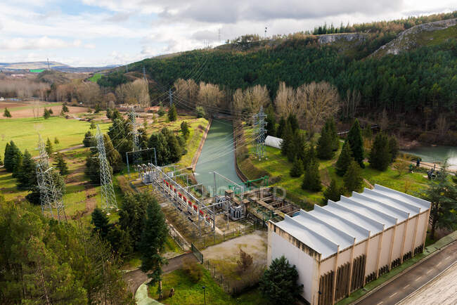 Зверху сучасна гідроелектростанція з водосховищем в зелених пагорбах — стокове фото