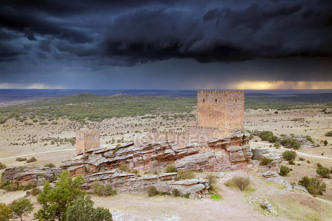 View of old stone fortress on rocks in picturesque terrain with dark stormy clouds on background, Spain — Stock Photo