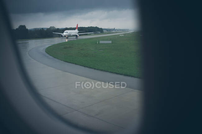 View from illuminator of aircraft on takeoff strip near green lawn in rainy weather in Austria — Stock Photo