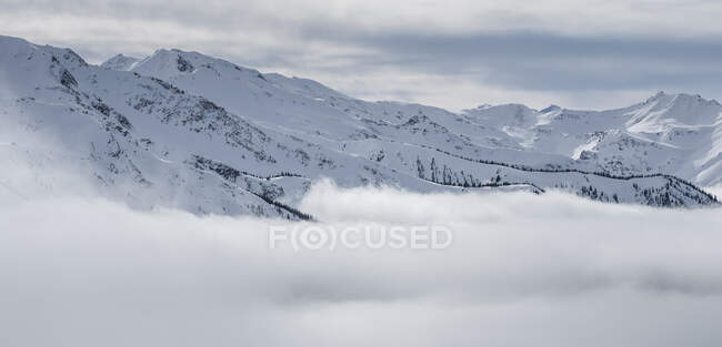 Pittoresca veduta della vetta delle montagne tra nuvole e neve in Canada — Foto stock