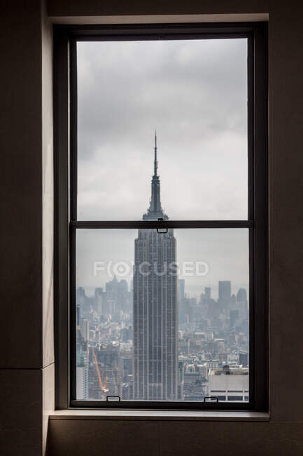 Toller Blick aus dem Fenster auf das Empire State Building in New York und wolkenverhangener Himmel — Stockfoto