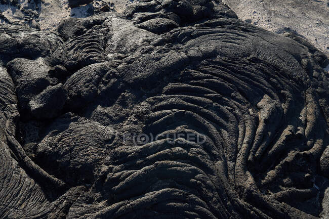 Closeup texture of dark rough rock in sunlight — Stock Photo