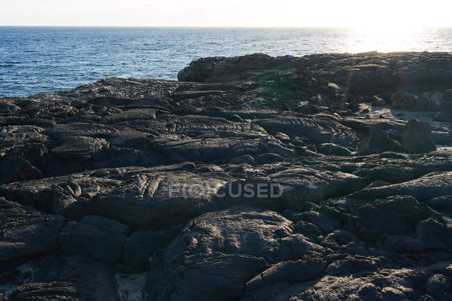 Côte rugueuse avec des rochers grogneux au bord de l'océan par temps ensoleillé — Photo de stock