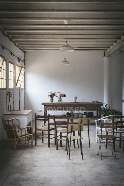 Світла гранжева кімната зі стільцями та дерев'яним столом з букетами свіжих квітів у вазах — стокове фото