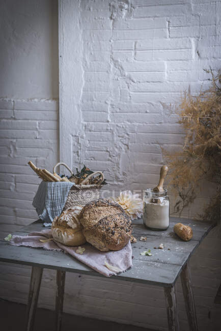 Bouquet de brindilles de conifères sèches suspendues sur la torsion au-dessus de la table avec boulangerie près des chaises dans la chambre — Photo de stock