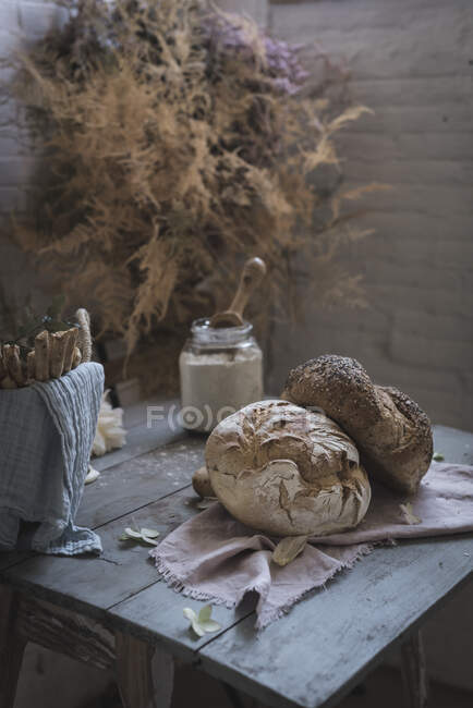 Bunch of dry coniferous twigs hanging on twist above table with bakery near chairs in room — Stock Photo