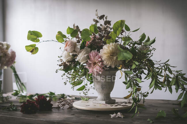 Konzept des Straußes aus trockenen und frischen Rosen, Chrysanthemen und Pflanzenzweigen in Retro-Vase auf Holzbrett auf grauem Hintergrund — Stockfoto