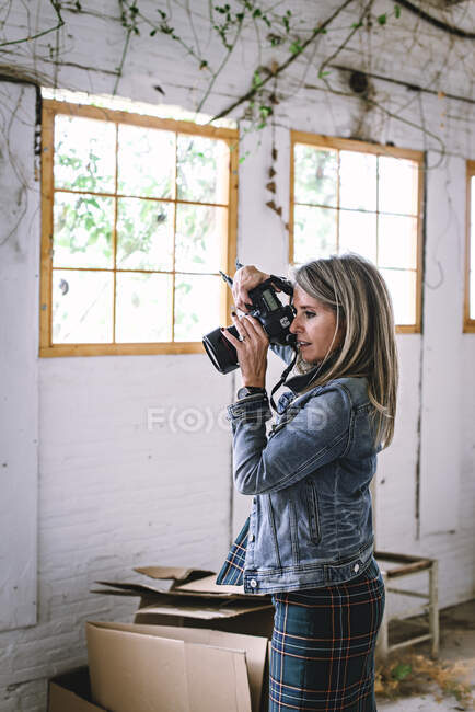 Frau fotografiert mit professioneller Kamera im Zimmer — Stockfoto