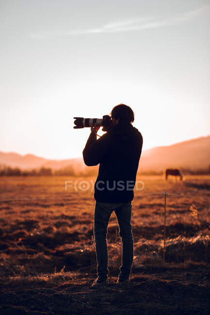 Back view of male taking photo of beautiful landscape between hills in sunny day in Cerdanya, France — Stock Photo