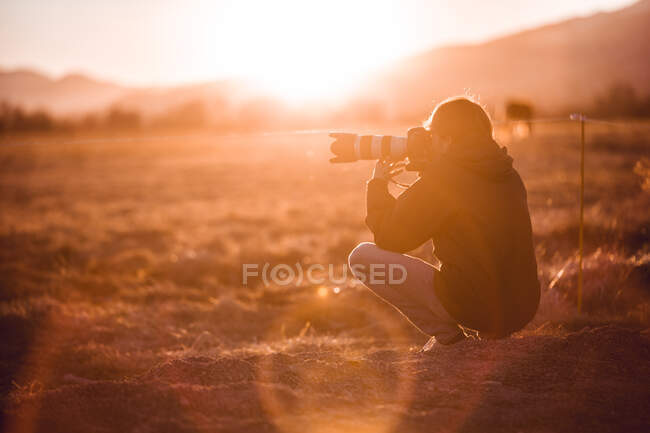 Vista posterior del macho tomando fotos de un hermoso paisaje entre colinas en un día soleado en Cerdanya, Francia - foto de stock