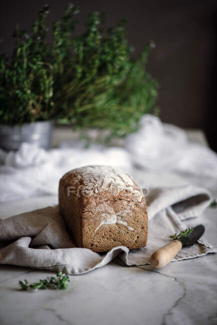 Délicieux pain de seigle aromatique frais sur serviette près du couteau sur fond flou — Photo de stock