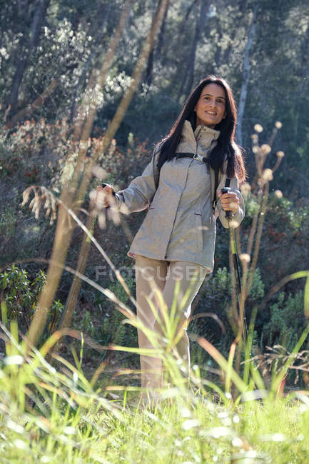 Femme heureuse avec des bâtons de trekking dans la forêt — Photo de stock