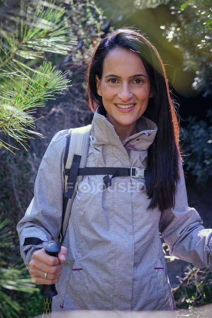 Glückliche Frau mit Trekkingstöcken im Wald — Stockfoto