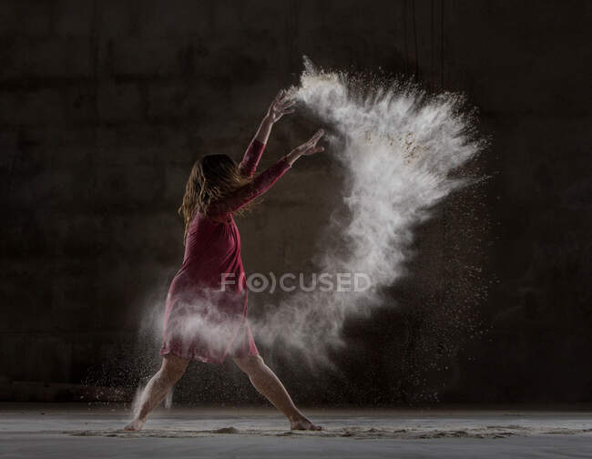 Junge Frau tanzt und benutzt Puder in der Dunkelheit — Stockfoto