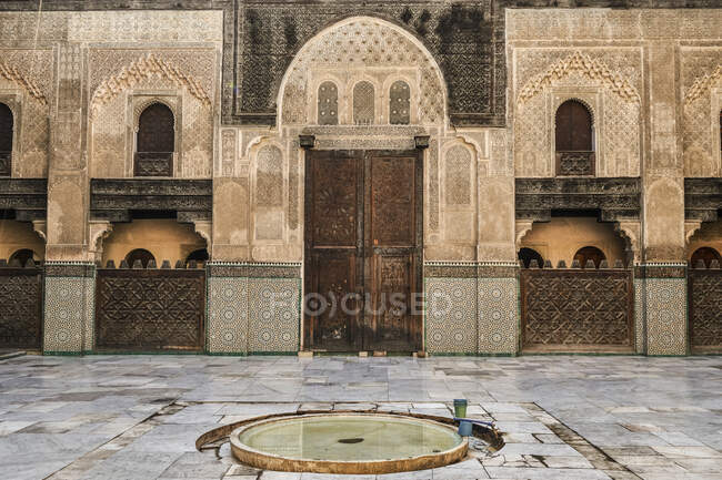 Grande recipiente com água entre a rua perto da fachada do antigo edifício de pedra com portas vintage em Marraquexe, Marrocos — Fotografia de Stock