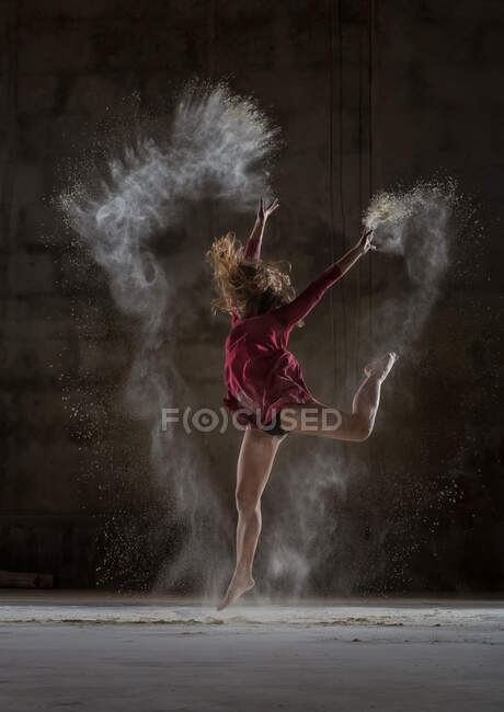 Молода жінка танцює і використовує порошок у темряві — стокове фото