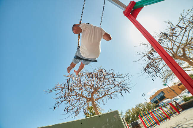 Homme se balançant sur une aire de jeux au soleil — Photo de stock