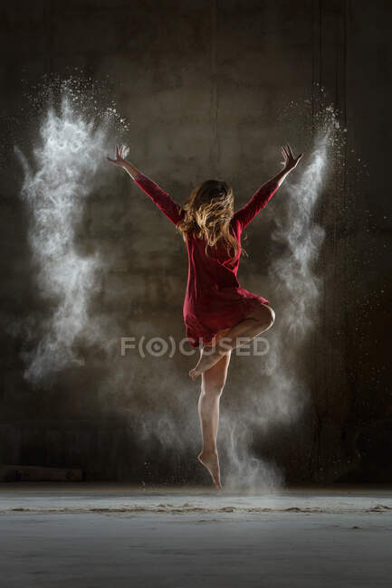 Mujer joven bailando y usando polvo en la oscuridad - foto de stock