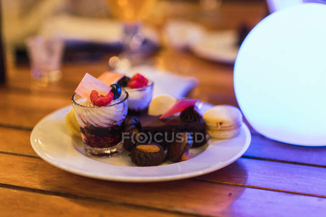 Керамическая тарелка с разнообразными вкусными десертами помещена на деревянный стол в ресторане в Дубае — стоковое фото