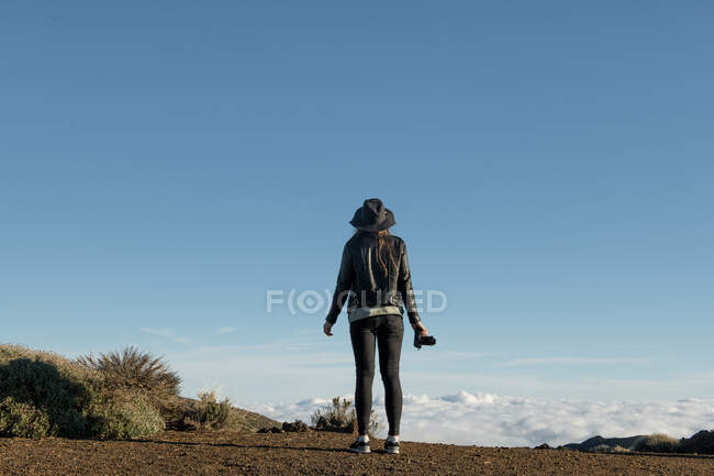 Back view of female photographer standing with camera and looking at hills in desert — Stock Photo
