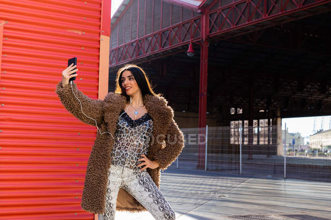 Femme branchée avec smartphone près du mur — Photo de stock