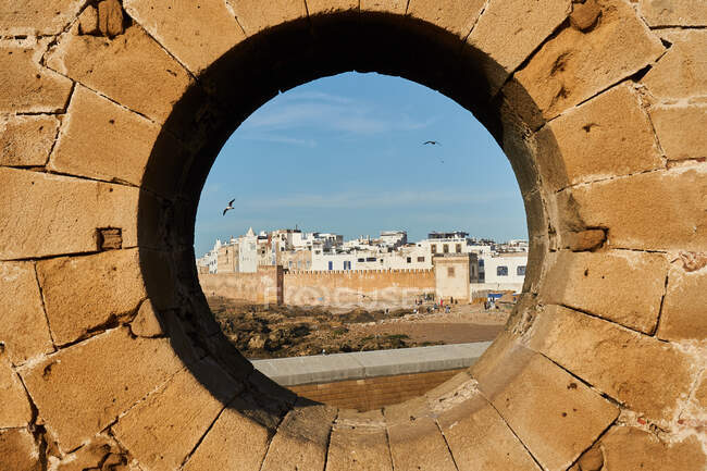 Abstraktes Felsendenkmal mit Kreisloch und malerischem Blick auf antike Stadt und blauen Himmel in Essaouira, Marokko — Stockfoto